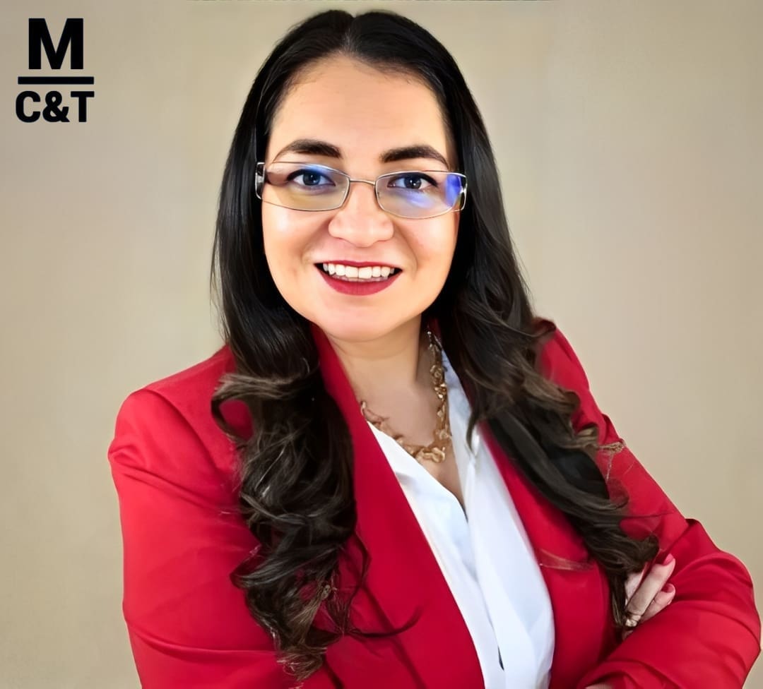 Smiling person in red blazer, glasses.