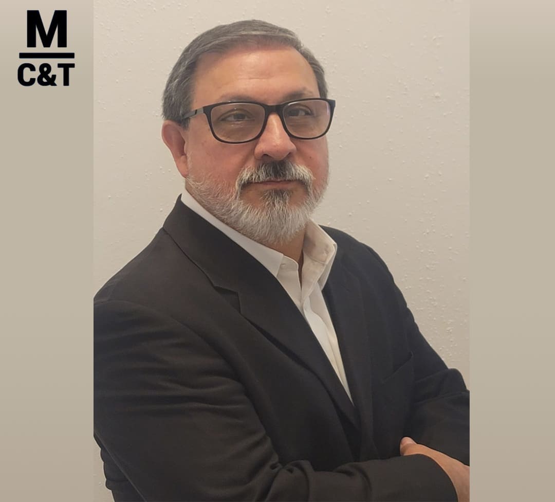 Man in suit with glasses, crossed arms.