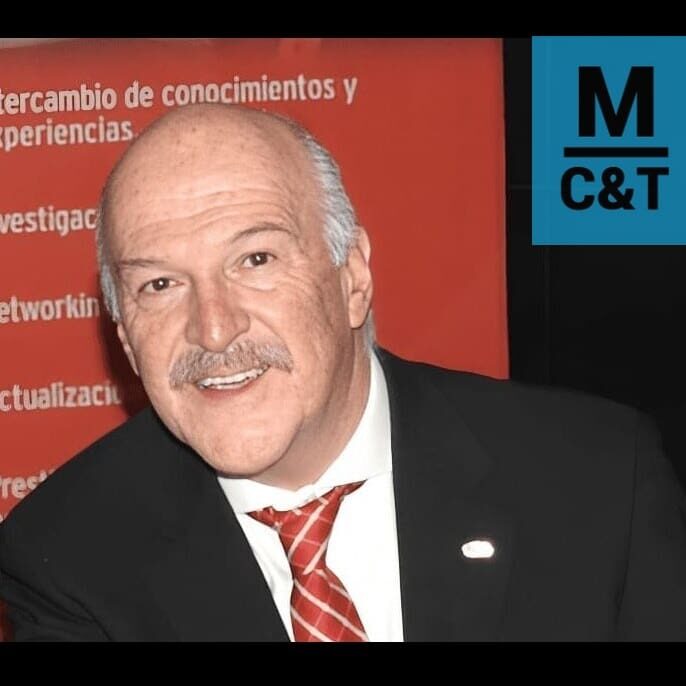 Man smiling in suit with red tie.